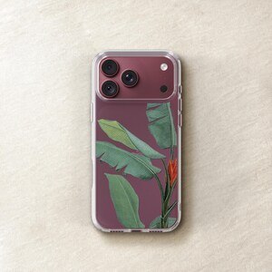 a clear phone case with a design of green leaves and a red flower on the back cover.