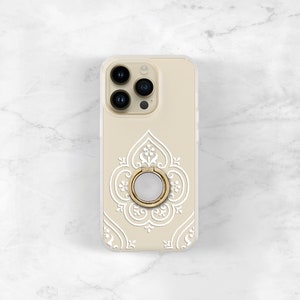 May include: A beige phone case with a white intricate design and a gold ring holder.