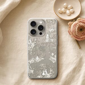 May include: A clear smartphone case featuring a white toile de jouy pattern with intricate illustrations of windmills, figures, and landscapes printed over a neutral gray background, designed for a triple-lens camera phone model.