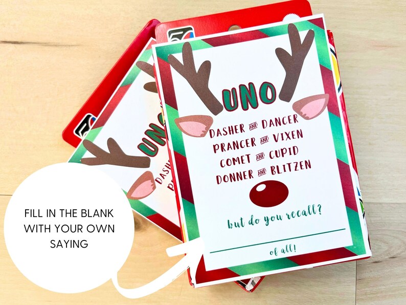 May include: A Christmas-themed Uno card game featuring reindeer antlers and ears. The cards display the word "UNO" and the names of Santa's reindeer. The text "Fill in the blank with your own saying" is also visible on the card.