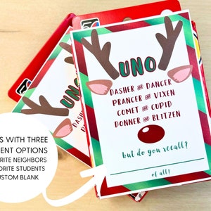 May include: A Christmas-themed Uno card game featuring reindeer antlers and the word "UNO." The card includes the text "Dasher and Dancer" and "but do you recall?" The game offers three options: favourite neighbours, students, or a custom blank. The game is red and green.