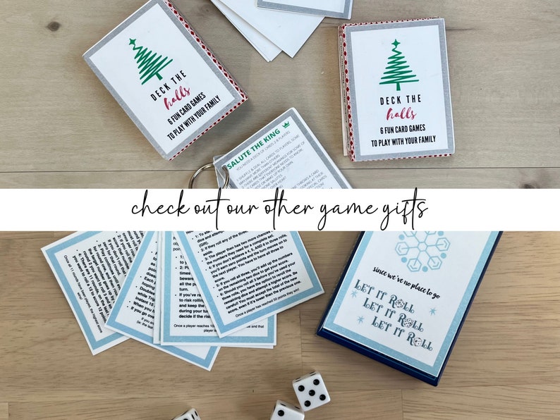 May include: Various card game sets with festive designs are arranged on a wooden surface. One set features "Deck the Halls" and a Christmas tree graphic. Another set has the text "Let it Roll". Dice are scattered nearby. The phrase "check out our other game gifts" is also visible.
