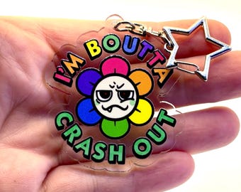 May include: A clear acrylic keychain with a colorful flower design and the text "I'M BOUTTA CRASH OUT". The keychain has a silver star-shaped clasp.
