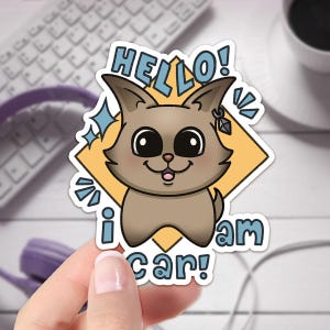 May include: A sticker featuring a cartoon brown dog with big eyes and a friendly smile. The dog is wearing a blue earring and is surrounded by a yellow diamond shape. The text "HELLO! I am car!" is written around the dog.