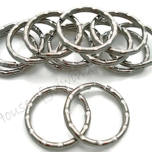 May include: A close-up of a pile of silver key rings. The key rings are all the same size and have a textured finish.