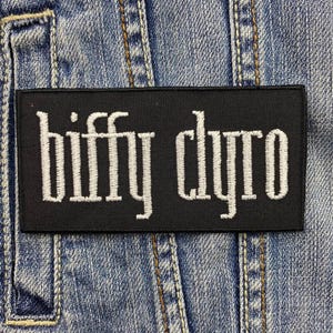 Op de afbeelding: Zwarte geborduurde patch met witte tekst "Biffy Clyro".