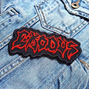 Op de afbeelding: Zwarte en rode geborduurde patch met het woord "GRAVE" in een gestileerd lettertype.