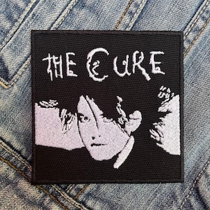 May include: Black and white embroidered patch with the text "THE CURE" and a stylized image of a person's face.