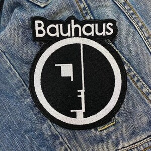 May include: Black and white embroidered patch with the word "Bauhaus" in white lettering and a stylized black and white geometric design.