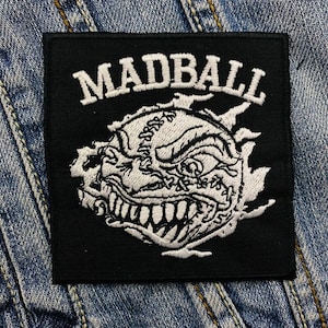 May include: Black and white embroidered patch with the text "MADBALL" and a white image of a snarling, stitched-up face.