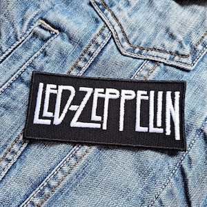Puede incluir: Parche bordado en blanco y negro con el texto "LED ZEPPELIN" sobre un fondo de mezclilla.