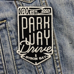 Könnte beinhalten: Schwarz-weiß gestickter Patch mit dem Text "Parkway Drive" und "Byron Bay" im Vintage-Stil. Der Patch enthält auch den Text "Est. 2003" und ein Logo.