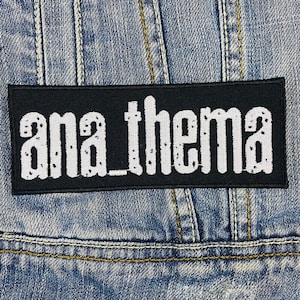 May include: Black patch with white text that reads "ana_thema" on a denim jacket.