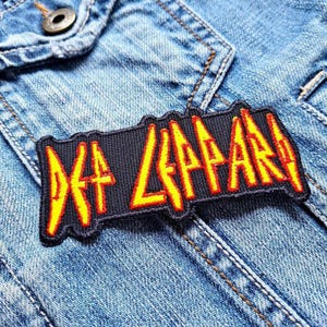 以下が含まれることがあります： デニムジャケットに「Def Leppard」という文字が書かれた黒と黄色の刺繍パッチ