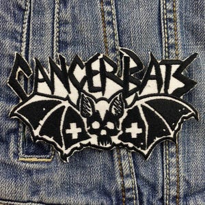 Peut inclure: Patch brodé noir et blanc avec le texte "Cancer Bats" et une chauve-souris avec un motif de crâne.