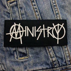 May include: Black patch with white embroidered text "Ministry" and a stylized anarchy symbol.