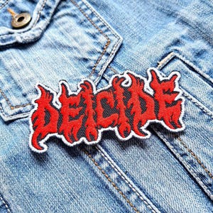 May include: Red and black embroidered patch with the word "DECIDE" in a stylized font. The patch is on a blue denim jacket.