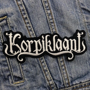 Op de afbeelding: Witte geborduurde patch met de tekst "Korpiklaani" in een zwart gotisch lettertype.