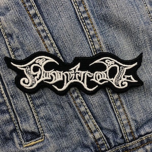 Puede incluir: Parche bordado en blanco y negro con la palabra "Slaughtercult" en una fuente estilizada.