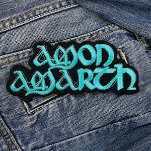 May include: A blue and black embroidered patch with the text "Amon Amarth" in a stylized font.