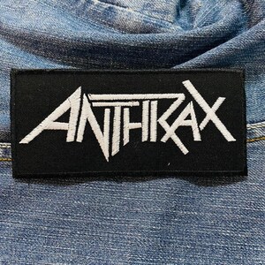May include: Black and white embroidered patch with the word "ANTHRAX" in a stylised font.
