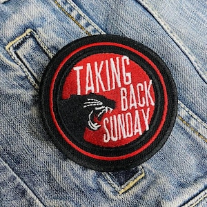 May include: A black and red embroidered patch featuring the text "Taking Back Sunday" and a black panther silhouette.