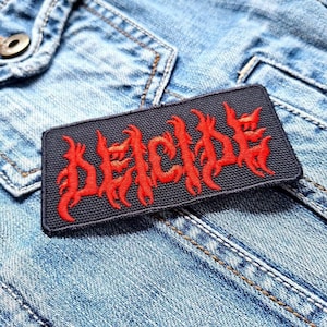 May include: A black and red embroidered patch with the word "DECIDE" in a stylized font.