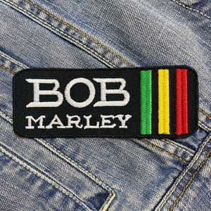 May include: Black and white embroidered patch with the text "BOB MARLEY" in white lettering. The patch has a green, yellow, and red stripe design on the right side.