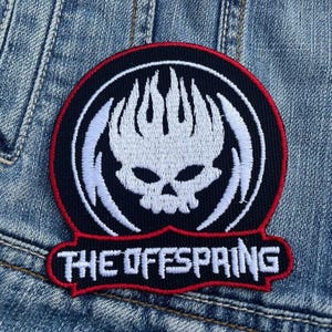May include: Black and white embroidered patch with a skull and flames design. The text "THE OFFSPRING" is embroidered in white on a red background.