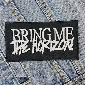 Può includere: Toppa ricamata in bianco e nero con il testo "Bring Me The Horizon" in un font stilizzato.
