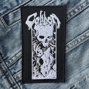 Op de afbeelding: Zwart-wit geborduurde patch met het woord "COLLISION" in gotische letter. De patch toont een schedel met een gedetailleerd ontwerp en een achtergrond van wijnstokken.