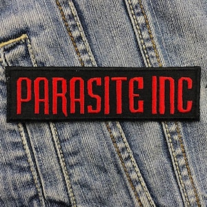 May include: Black patch with red embroidered text that reads "PARASITE INC."