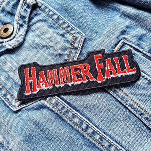 May include: A black and red embroidered patch with the text "HAMMERFALL" on a denim background.