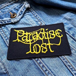 May include: Black fabric patch with the words "Paradise Lost" embroidered in yellow.