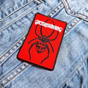 May include: Red embroidered patch with a black spider and the text "In This Moment" in white.