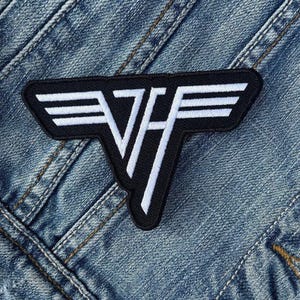 Op de afbeelding: Zwart en wit geborduurde patch met het Van Halen logo. De patch heeft de vorm van een gestileerde "VH" met witte strepen en letters op een zwarte achtergrond. Genaaid op een spijkerjasje.