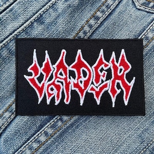 Pode incluir: Patch preto com a palavra "VADER" em letras brancas com contorno vermelho.