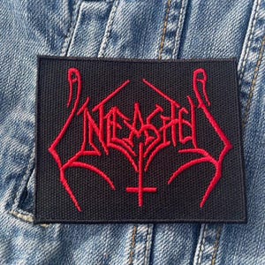 May include: Black iron-on patch with a red embroidered logo that says "NETHER" in a gothic font. The logo is surrounded by two red hands with the index fingers pointing up.