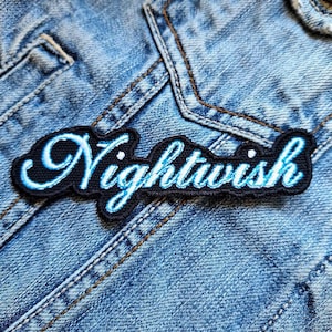 Könnte beinhalten: Ein gestickter schwarzer und blauer Aufnäher mit dem Wort "Nightwish" in einer kursivschrift.