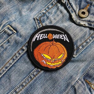 May include: A black and orange embroidered patch featuring a pumpkin and the text "HELLOWEEN" in white.
