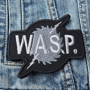 Può includere: Toppa ricamata in bianco e nero con la parola "WASP" in lettere bianche e un design a fulmine stilizzato.