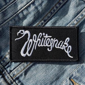 Könnte beinhalten: Schwarzer Patch mit weiß gesticktem Text, der "White Snake" lautet.