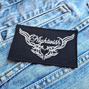 Op de afbeelding: Een zwarte geborduurde patch met een wit hartontwerp en de tekst "Nightwish" in een gestileerd lettertype.
