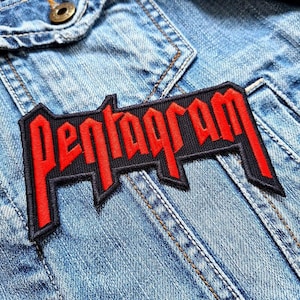Peut inclure: Patch brodé rouge et noir avec le mot "Pentagram" dans une police audacieuse et stylisée. Le patch est cousu sur une veste en jean bleue.