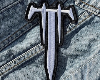May include: White embroidered patch of a triple-headed sword on a blue denim background.