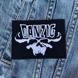 May include: Black and white embroidered patch with the word "DANZIG" in white lettering and a skull design.
