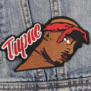 Puede incluir: Parche de planchado bordado con un retrato del rapero Tupac Shakur con la palabra "Tupac" en letras rojas y blancas.