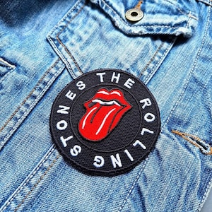 Könnte beinhalten: Ein gestickter schwarzer und weißer Aufnäher mit dem Text "The Rolling Stones" in einem Kreis um ein rotes und weißes Zungenlogo.