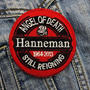 Puede incluir: Parche rojo bordado con el texto "Angel of Death Hanneman 1964-2013 Still Reigning" en letras blancas y negras.