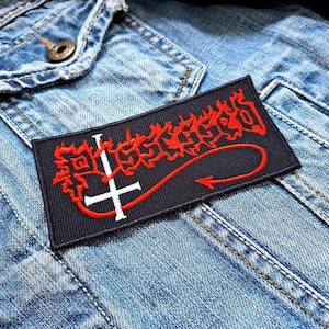 May include: Black and red embroidered patch with the text "SLAUGHTER" in a stylised font. The patch features a white upside-down cross with a red tail.